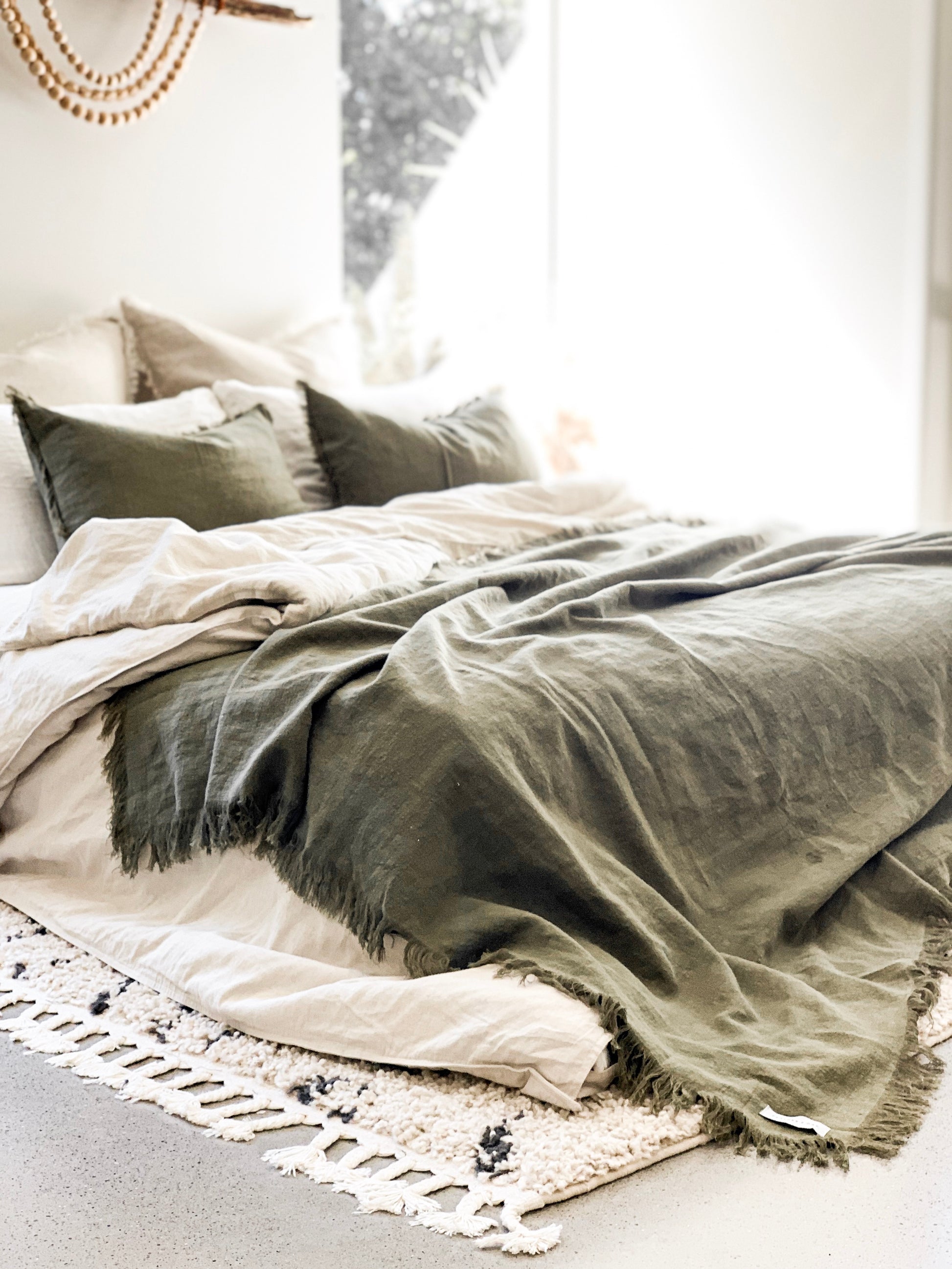 RAMIE FRINGED THROW BLANKET - OLIVE / GREEN. Made from 100% ramie & hand-finished with a soft, fringed border for a relaxed look & feel. The extra-long design drapes generously over either side of your bed, creating a cozy, layered look. Available in Queen & King size.